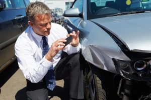 a man taking a picture of a car for an mib claim