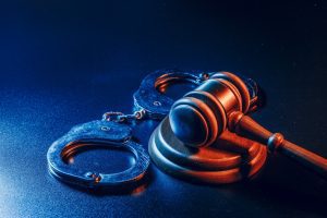 Blue lighting which shows a gavel and handcuffs on a table
