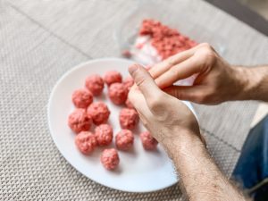 A plate full of raw mince meat balls being prepared.