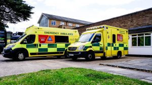 Two ambulances are parked outside a hospital. 