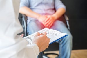 A man with a groin injury sits in a wheelchair and talks to a doctor