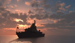 A naval vessel in the ocean at sunset.