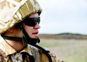 A close-up image of a soldier in full desert uniform and dark glasses.