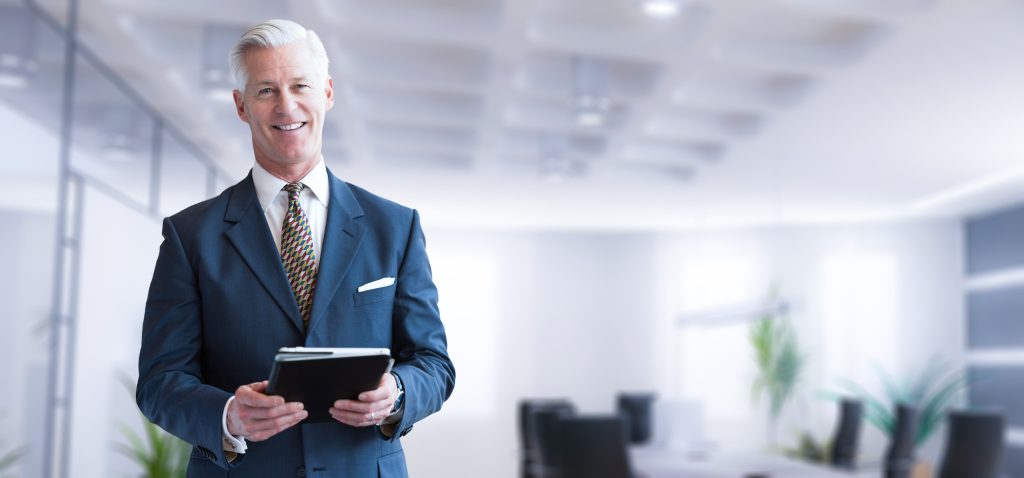 A military injury claim solicitor in a blue suit standing in an office.