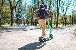 A road user riding an e-scooter through a park. 