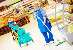 A shop worker cleans a supermarket floor.