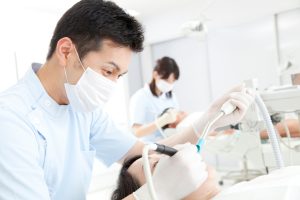 DENTIST TREATING A CLIENT IN A CHAIR AT A DENTAL PRACTICE