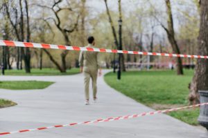 Part of a park is cordoned off by security tape. A person walks behind this tape. 