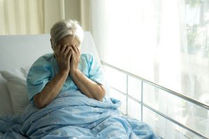 An elderly woman on a bed in a care home. 