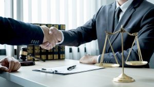 a medical negligence solicitor shakes a client's hand over a desk and contract. 