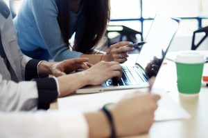 People sit at a desk looking at a computer.