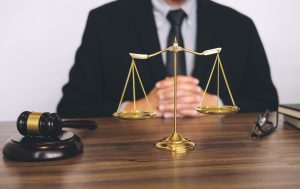 A solicitor sits at a desk with a scale and gavel on it. 