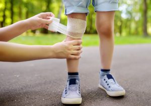 An injured child has their knee bandaged. 