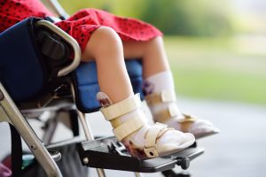 An injured child sits with their legs in braces.