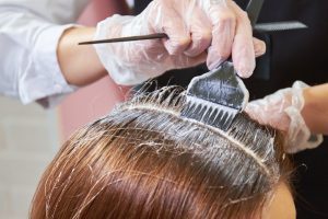 PERSON HAVING HAIR DYE TREATMENT AT BEAUTY SALON