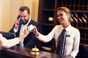 IMAGE OF HOTEL FRONT DESK AND STAFF HANDING KEYS OVER