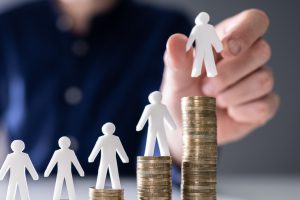 Plastic figures on top stacks of coins showing child accident compensation. 