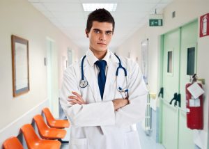 Doctor in hospital with crossed arms and stethoscope around his neck 