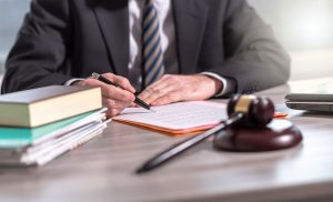 Accident claims solicitor signing a document for a neck injury claim, with papers and gavel on the desk