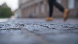 Person walking on a broken pavement which could cause pavement accident claims.