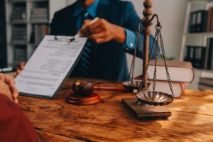 A solicitor and their client at a desk with a set of justice scales and gavel hammer discussing dental negligence compensation claims