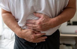 IMAGE OF A MAN SUFFERING FOOD POISONING AND CLUTCHING STOMACH