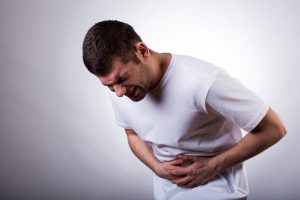 PERSON HOLDING HIS STOMACH BECAUSE OF SUFFERING FOOD POISONING