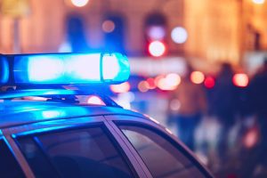 A police car on the street flashes its blue lights at night.